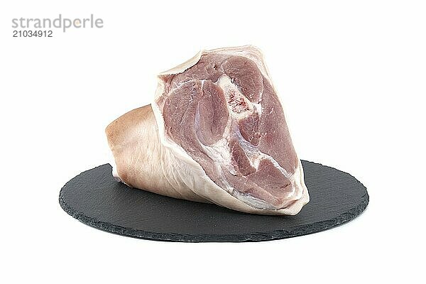 Fresh raw pork shank on black stone plate over white background