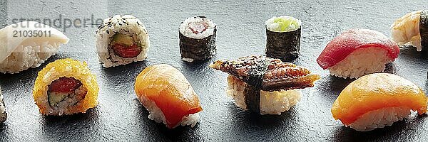 Sushi panorama. Nigiri with eel  salmon and tuna  roll with avocado and maki with cucumber on a black background  Japanese food on a plate at an Asian restaurant