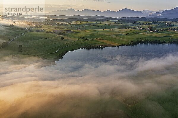 Aerial view of a lake in front of mountains in the morning light  fog  autumn  Riegsee  view of Benediktenwand and Joch  Alpine foothills  Upper Bavaria  Bavaria  Germany  Europe