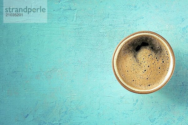 A cup of black coffee with froth  overhead flat lay shot on a blue background  with a place for text  Food photography  Food photography