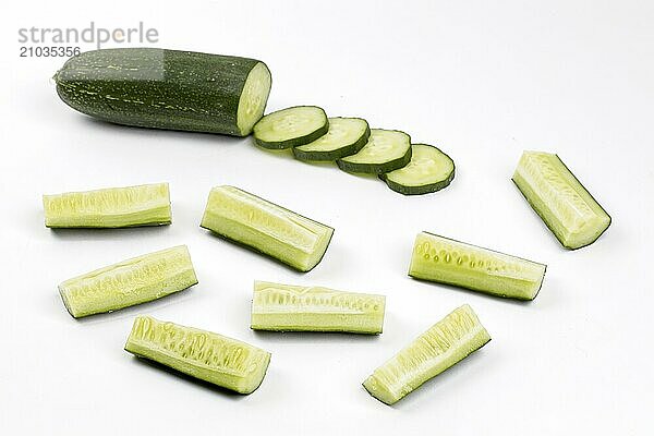 A close up photo of whole  sliced  and cut up pieces of cucumber on a white background