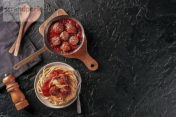 Meatballs. Beef meat balls  overhead flat lay shot in a pan and with a plate of spaghetti pasta  on a black background  with copy space  Food photography  Food photography