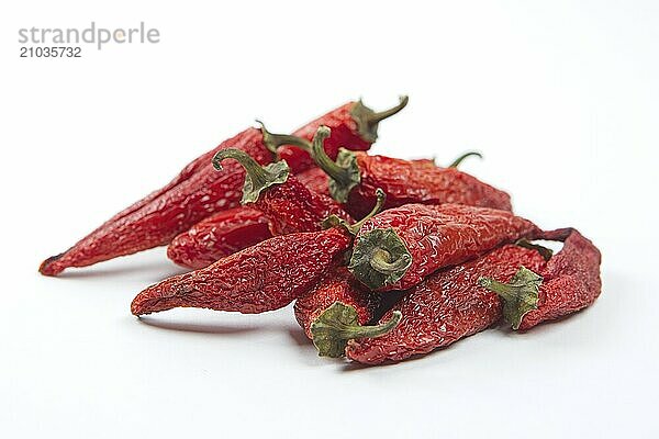 A pile of partially dried spicy red peppers on on a clean white background