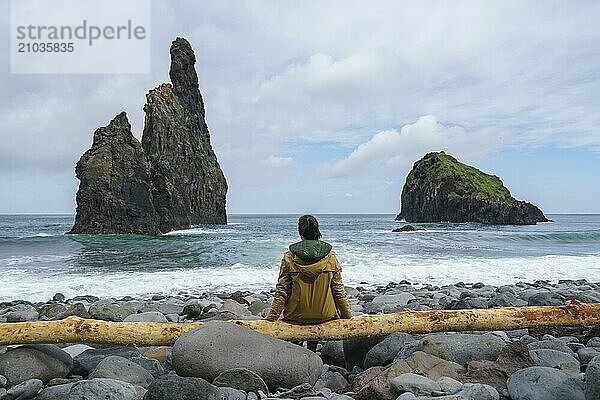 Janela Islets in Porto Moniz in Madeira with a woman sitted on a yellow tree on the ground