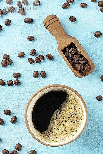 Coffee cup and beans in a scoop  shot from above on a vibrant blue background