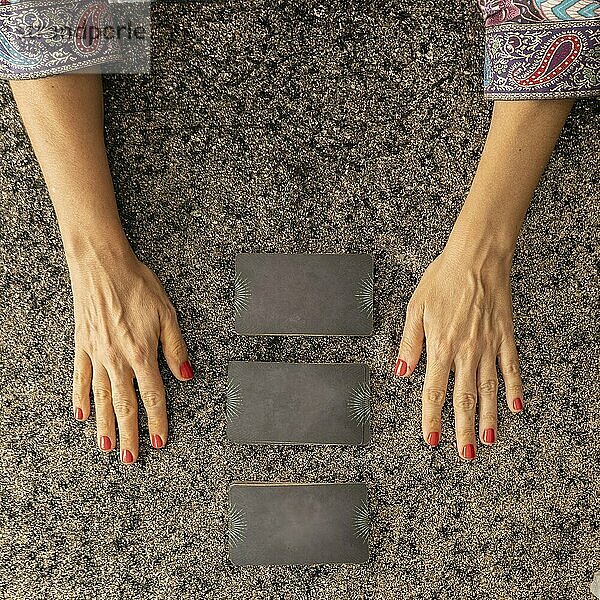 Top view of a tarot reader's hands and three cards turned face down