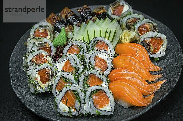 Sushi  traditional Japanese cuisine. Several delicious sushi on the decorated plate  black background. Group of sushi  Urakami  Nigori  Sushi jow  sashimi  tekamaki  etc