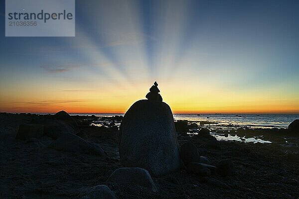 Stone pyramid on the Baltic Sea overlooking the sea at sunset. Sun shines behind stone pyramid. Stones as silhouette. Spiritual view. Landscape shot from Poel island