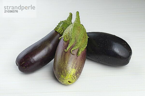 Sill life photo of three large eggplants positioned on a white background