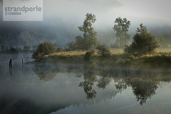 Fog and mist layers lightly covers the calm mirror like St. Joe River near St. Maries  Idaho