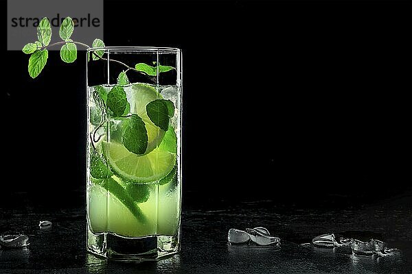 Mojito cocktail. Summer cold drink with lime  fresh mint  and ice. Cool beverage  side view on a black background with copy space  Food photography  Food photography