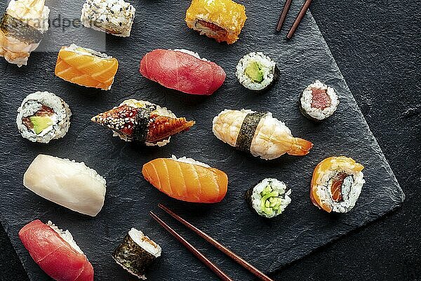 Sushi overhead flat lay shot with chopsticks. Rolls  maki  nigiri on a black background  Japanese food. Salmon  tuna  eel  shrimp and other seafood with rice on a plate at an Asian restaurant  Food photography  Food photography