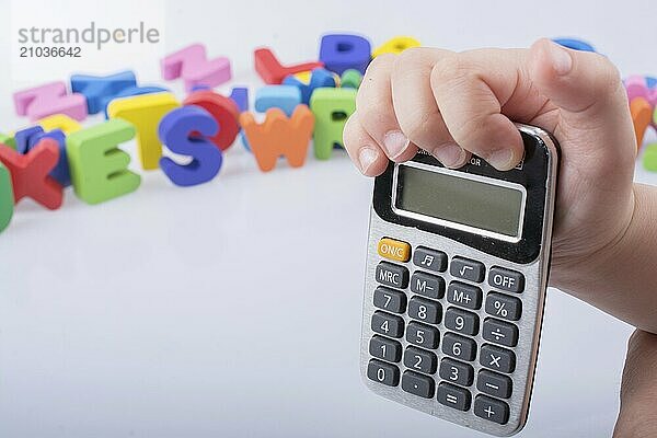 Little calculator in hand with colorful letters behind on white