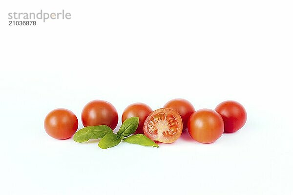 Red cherry tomatoes with green basil on a white background.