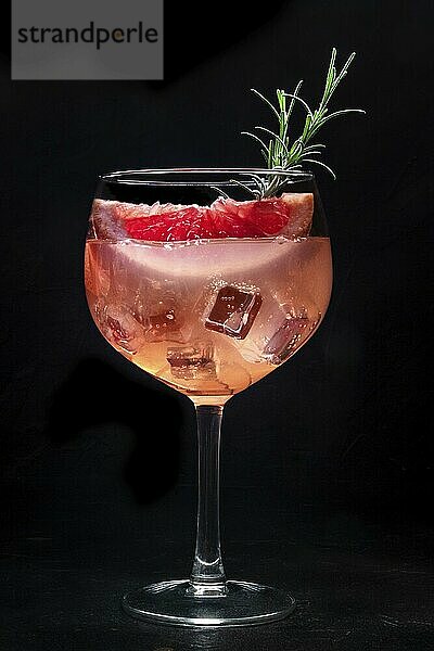 Cocktail with fresh fruit. Gin and tonic drink with ice at a party  on a black background. Alcohol with pink graperfuit and rosemary  Food photography  Food photography