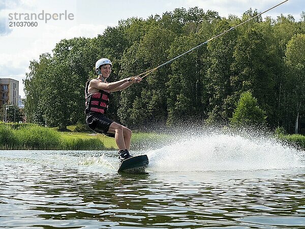 Young man on wakeboard in splashing water  cheerful  water skiing and wakepark  water sports  Stráž pod Ralskem  Czech Republic  Europe