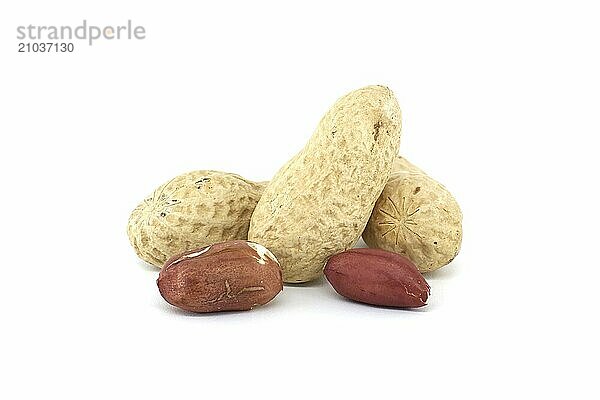 Pile of shelled and unshelled dried peanuts scattered on white background