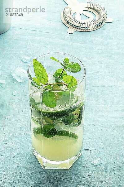 Mojito cocktail. Summer cold drink with lime  fresh mint  and ice. Cool beverage on a blue background  with a strainer  Food photography