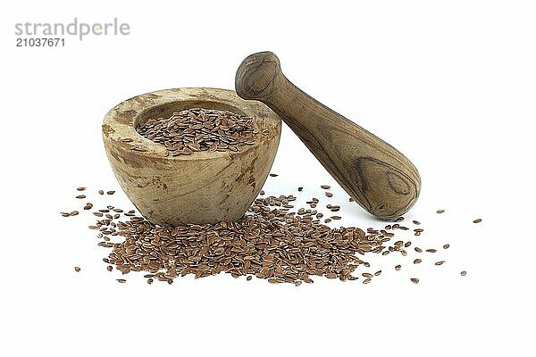 Linseed in wooden rustic-style mortar with pestle isolated on white background. Linum usitatissimum (Common Flax)