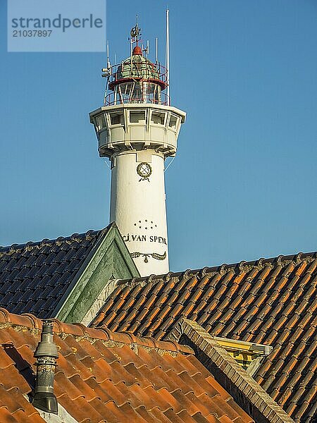 Lighthouse behind red tiled roofs on a clear day  egmond aan zee  the netherlands