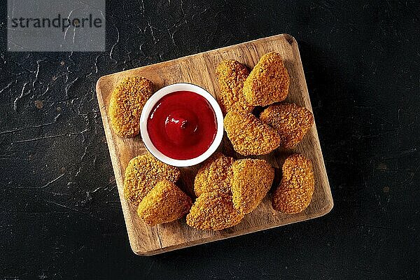 Chicken nuggets with ketchup on a black background  overhead flat lay shot. A crispy meat snack at a restaurant  a fast food dish  Food photography