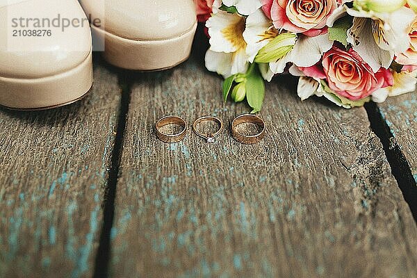 Wedding rings  shoes and bouquet on the wooden background.