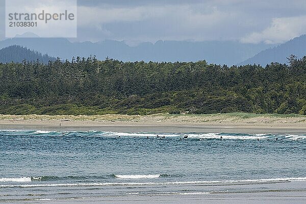 A group of surfers stand in the surf at Wickaninnish Beach on Vancouver Island