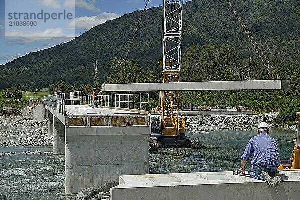 Builders construct a concrete bridge over a small river in Westland  New Zealand  Oceania