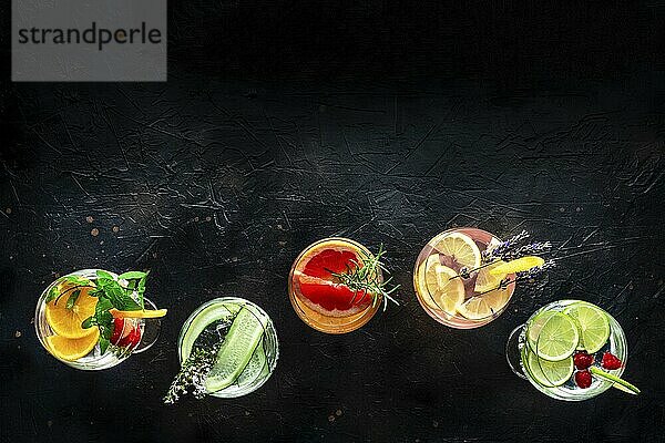 Fancy cocktails with fresh fruit. Gin and tonic drinks with ice at a party  on a black background  shot from the top with copy space  Food photography