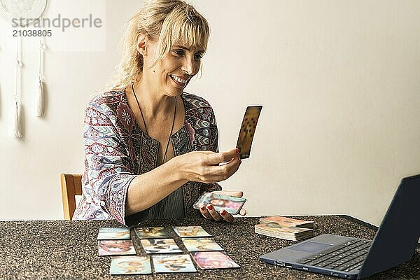 Tarot reader showing the laptop screen with the revealed card during her online session