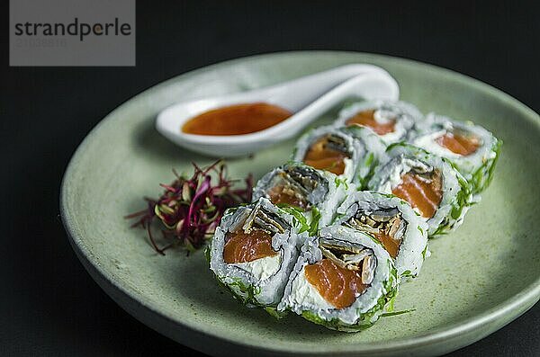 Perfect sushi  traditional Japanese cuisine. Delicious uramaki with sweet and sour sauce on the decorated plate  black background