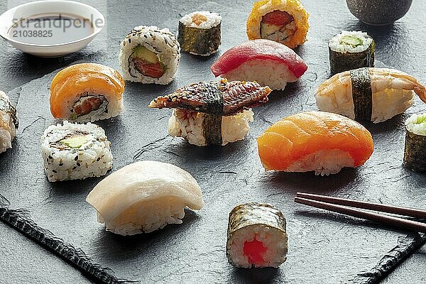 Sushi with chopsticks. Rolls  maki  nigiri on a black background  Japanese food. Salmon  tuna  eel  shrimp and other seafood with rice on a plate at an Asian restaurant  Food photography  Food photography