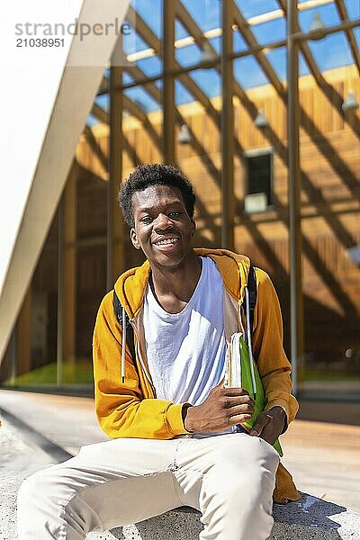 Vertical portrait with copy space of a happy african american man sitting outside the university