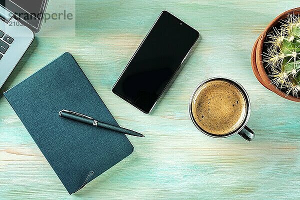 Desk  top view on a wooden blue background. Coffee  notebook  phone  plant  and laptop  overhead flat lay shot. Work layout  Food photography