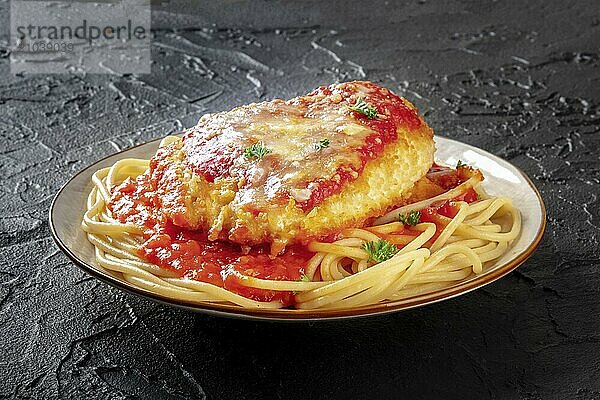 Chicken Parmesan  Italian pasta dish. Breaded chicken breast with cheese and spaghetti with tomato sauce  the plate is on a dark background