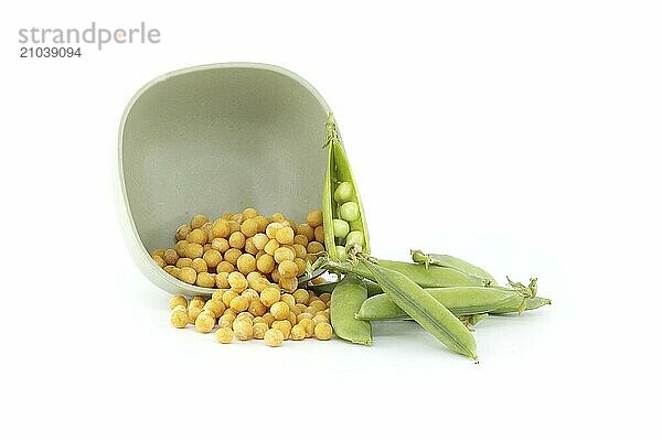 Fresh green garden peas and a bowl filled with dried whole yellow peas isolated on white background