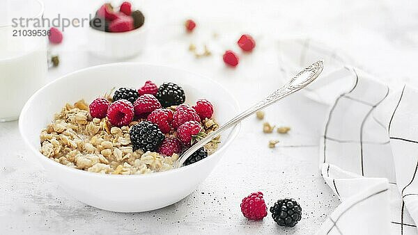 Morning healthy breakfast  white bowl full with granola  muesli  raspberry  blackberry on gray concrete table. Healthy eating  eco  bio food concept. Fresh tasty meal on grey background. Quality photo