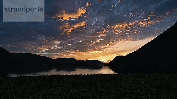 Fjord with sunset and illuminated clouds in the sky. View of mountains and fjord landscape in Norway. Landscape shot in the evening in the north