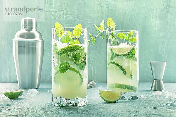 Mojito cocktail. Summer cold drink with lime  fresh mint  and ice. Cool beverage on a blue background  side view with a shaker  Food photography