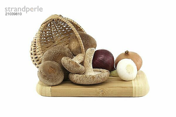 Shiitake mushrooms and various kinds of onions on a wooden cutting board over on white background. Recipes and medicinal herbs