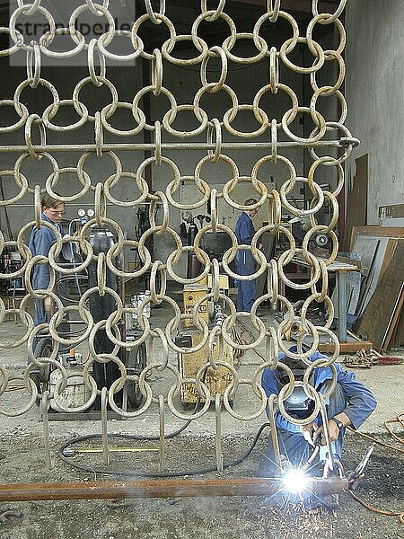 Man welding circular links on harrows for farm