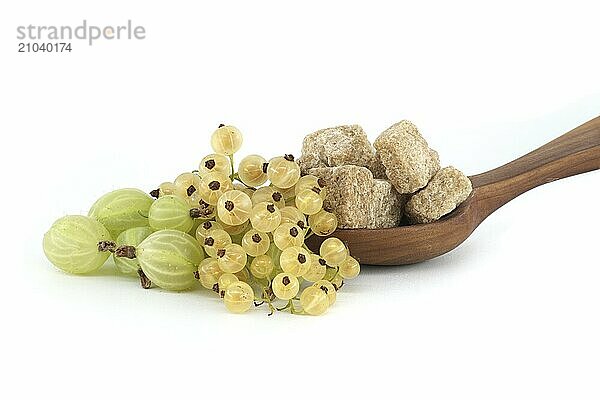 Gooseberries and yellow currants next to brown cane sugar cubes in wooden bowl  isolated on white background  berry jam  compote preparation