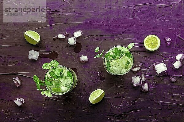 Mojito cocktail  overhead flat lay shot. Summer cold drink with lime  fresh mint  and ice. Cool beverage on a purple background  Food photography