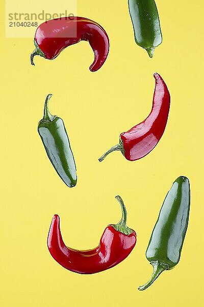 Red and green jalapeno peppers set against a yellow background