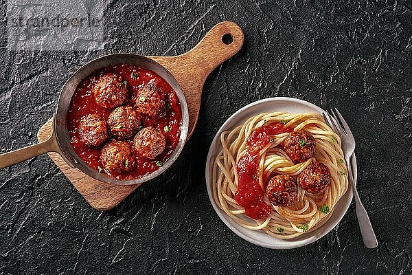 Meatballs. Beef meat balls  Italian dish  overhead flat lay shot in a pan and with a plate of spaghetti pasta  on a black background  Food photography