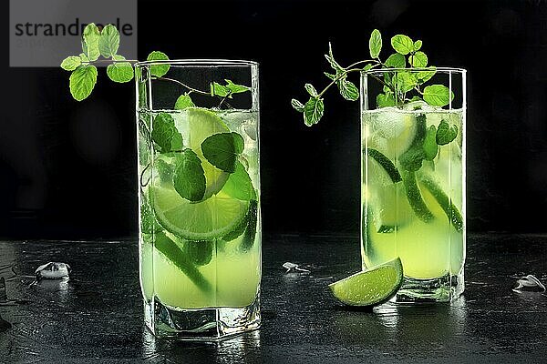 Mojito cocktail  two glasses. Summer cold drink with lime  fresh mint  and ice. Cool beverage  side view on a black background  Food photography  Food photography