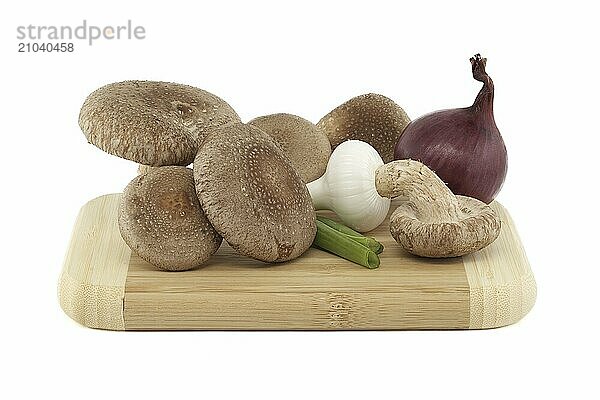 Fresh shiitake mushrooms  various onions on a wooden cutting board isolated on white background. Fungi recipes and medicinal herbs