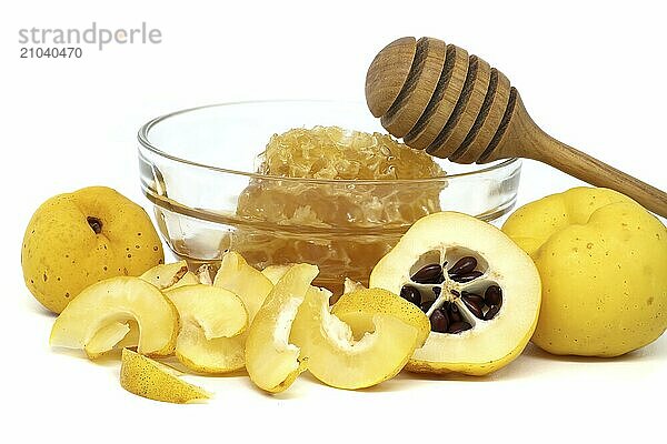 Glass bowl brimming with honey and wooden dipper resting on its rim surrounded by vibrant quince fruits  both sliced and whole isolated on white background  full depth of field