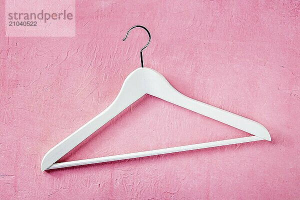 Fashion collection concept. A white wooden hanger  flat lay on a pink background. Shopping  abstract design  Food photography