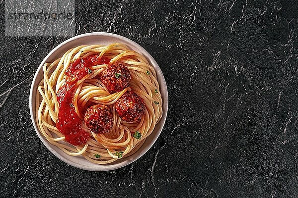 Meatballs. Beef meat balls  overhead flat lay shot with spaghetti pasta  parsley  and tomato sauce  on a black background  with a place for text  Food photography